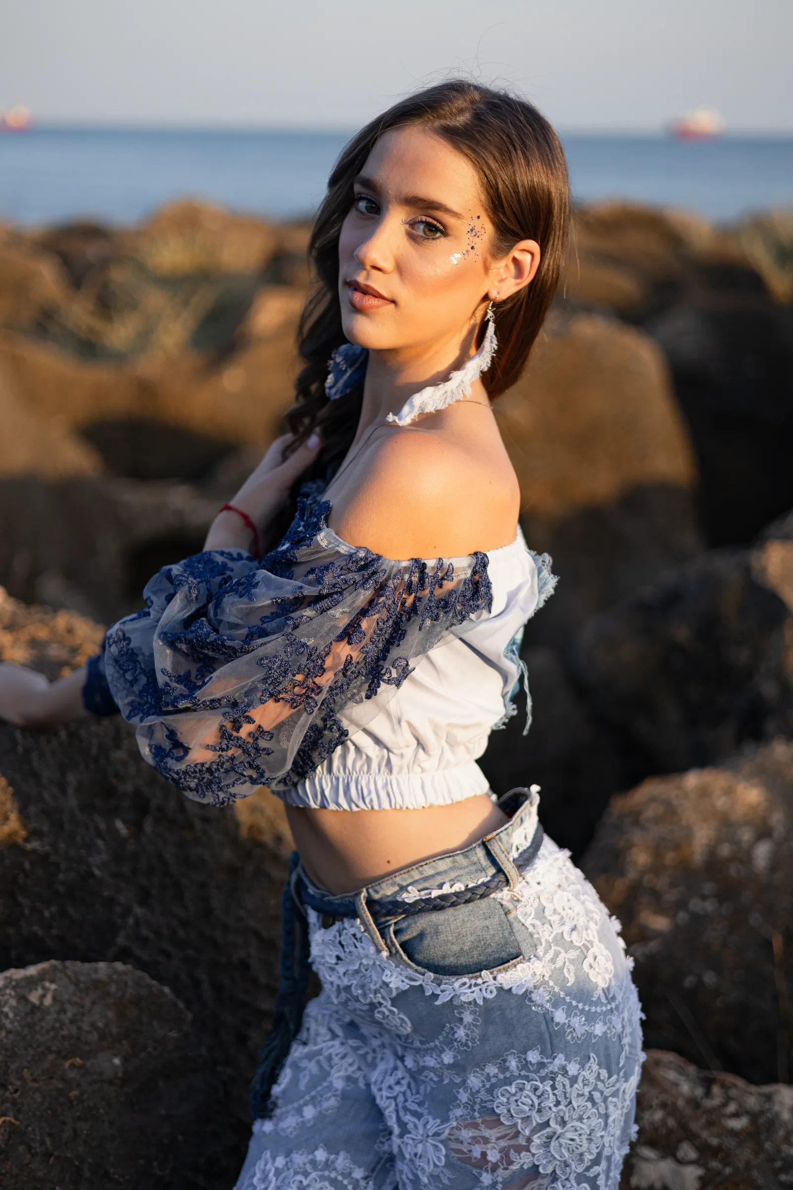 Two models in lace and denim on the rocks at sunrise